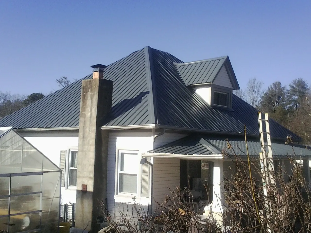 Dark blue standing seam metal roof on a white farmhouse with dormer — Slate & Tile Roof Repair by Roofing Brothers in Curwensville