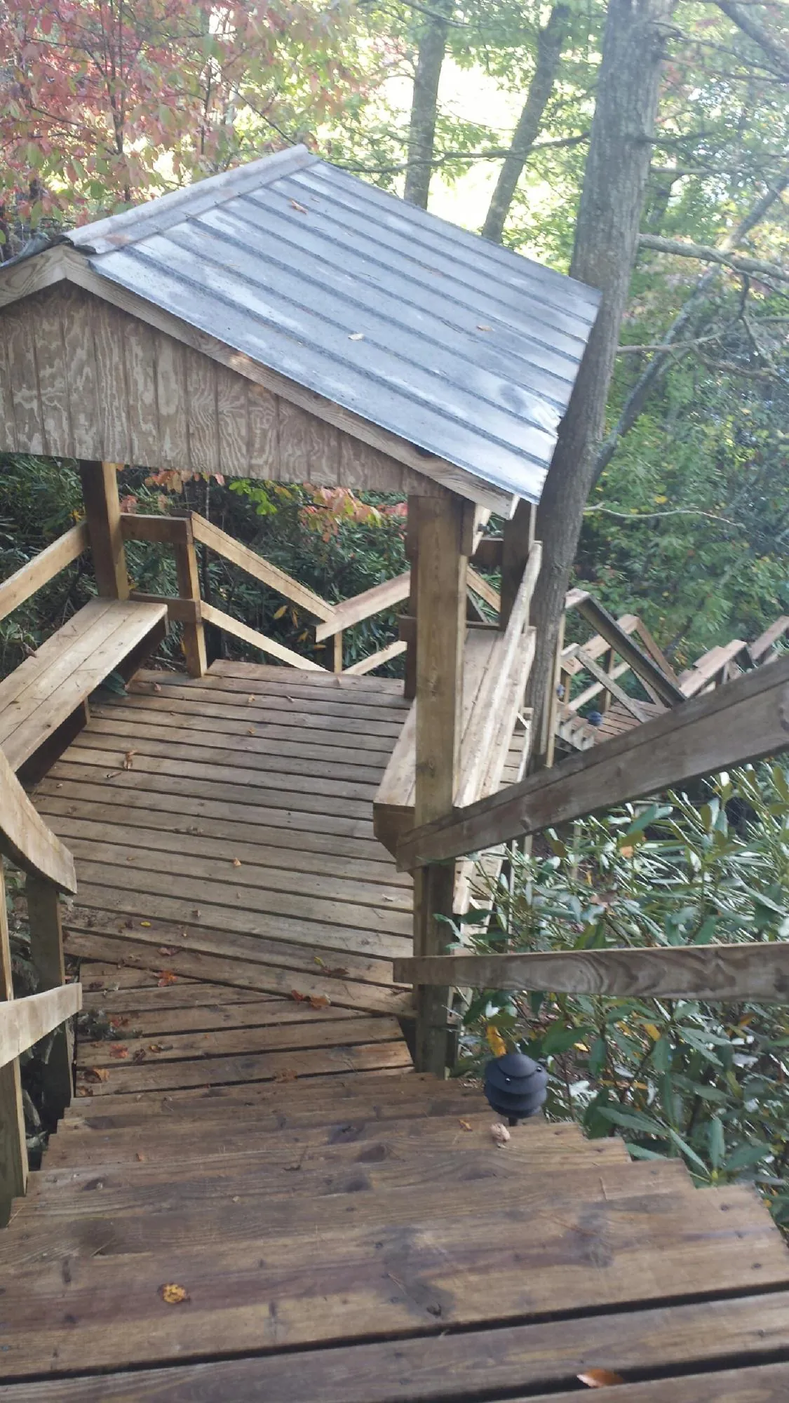Metal roofed shelter over wooden steps on a wooded walkway — Skylight Repair & Installation work by our crew in Curwensville