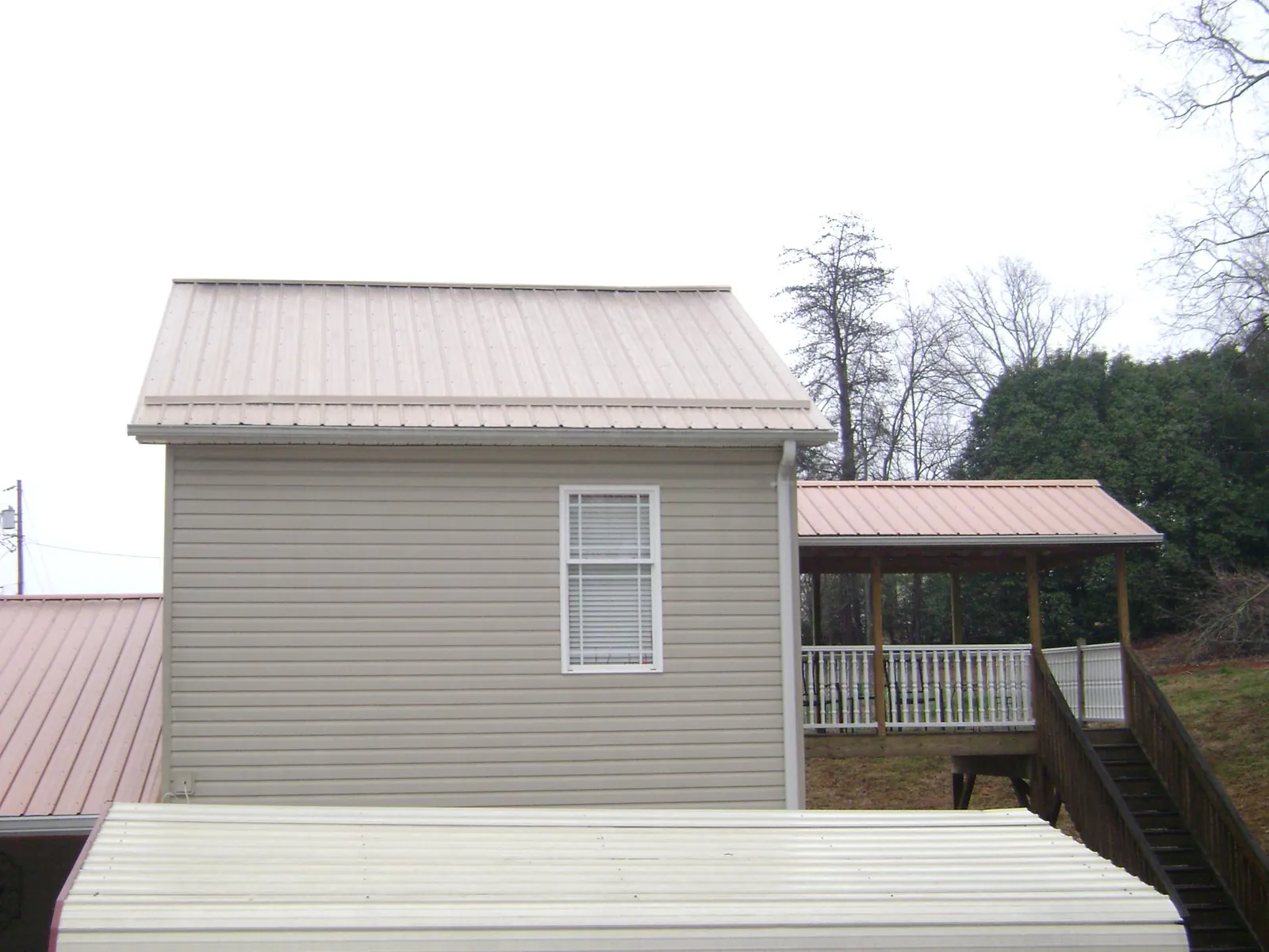 Tan metal roofs on a two story addition and attached porch, from a Roof Replacement job in Curwensville