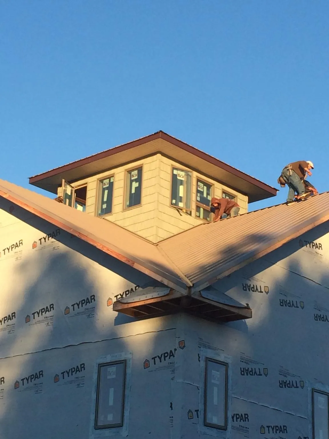 Roofers working around a rooftop cupola on a new metal roof at sunset — Roof Waterproofing in Curwensville by Roofing Brothers